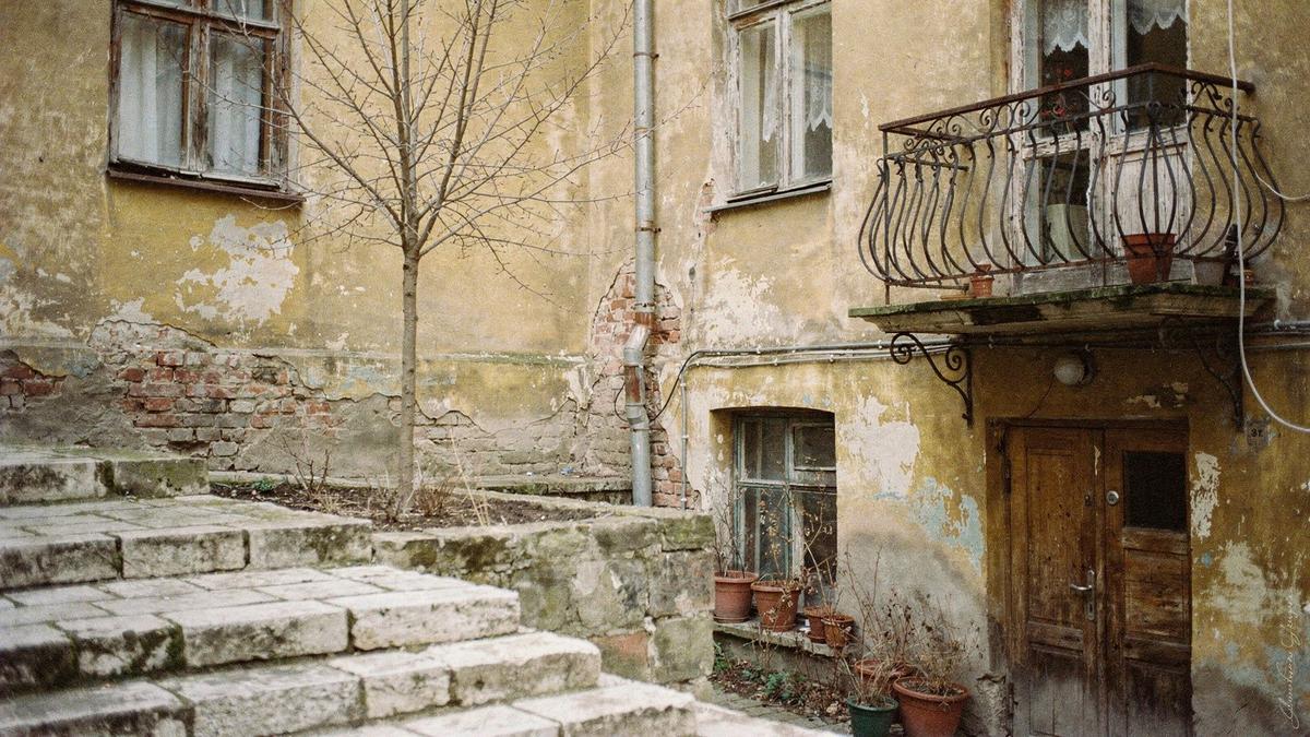 Quiet Lviv courtyard with worn stone steps and an iron balcony